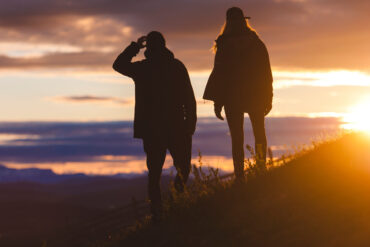 two people watching sunset over mountain