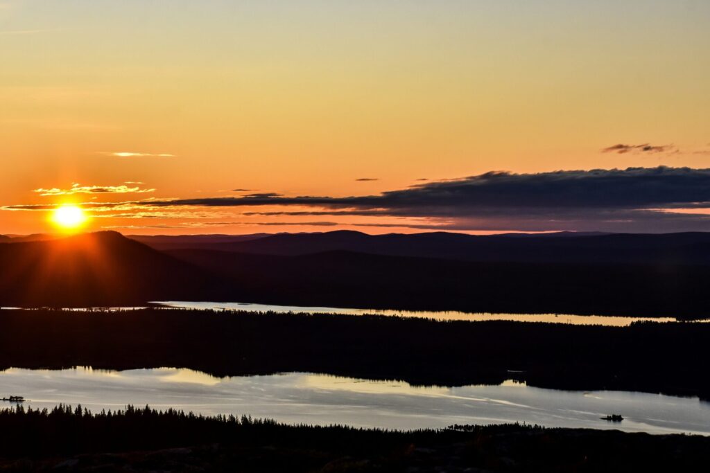 sun setting over mountains by river