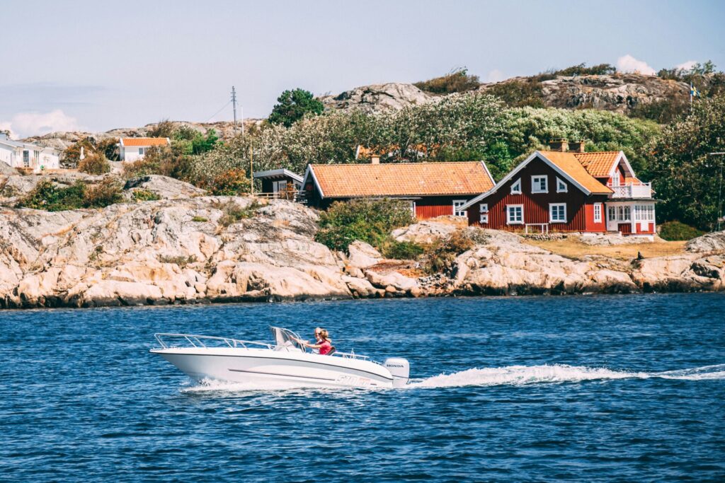 white speedboat in front of a red house 
