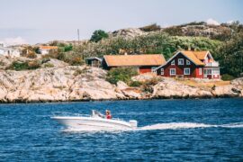 white speedboat in front of a red house