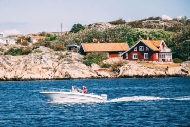 white speedboat in front of a red house