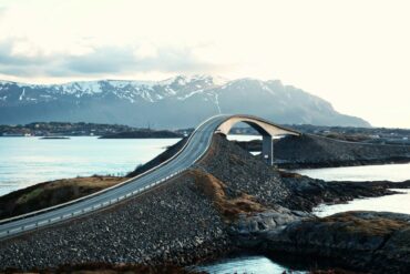 road floating over the sea with mountains in the back