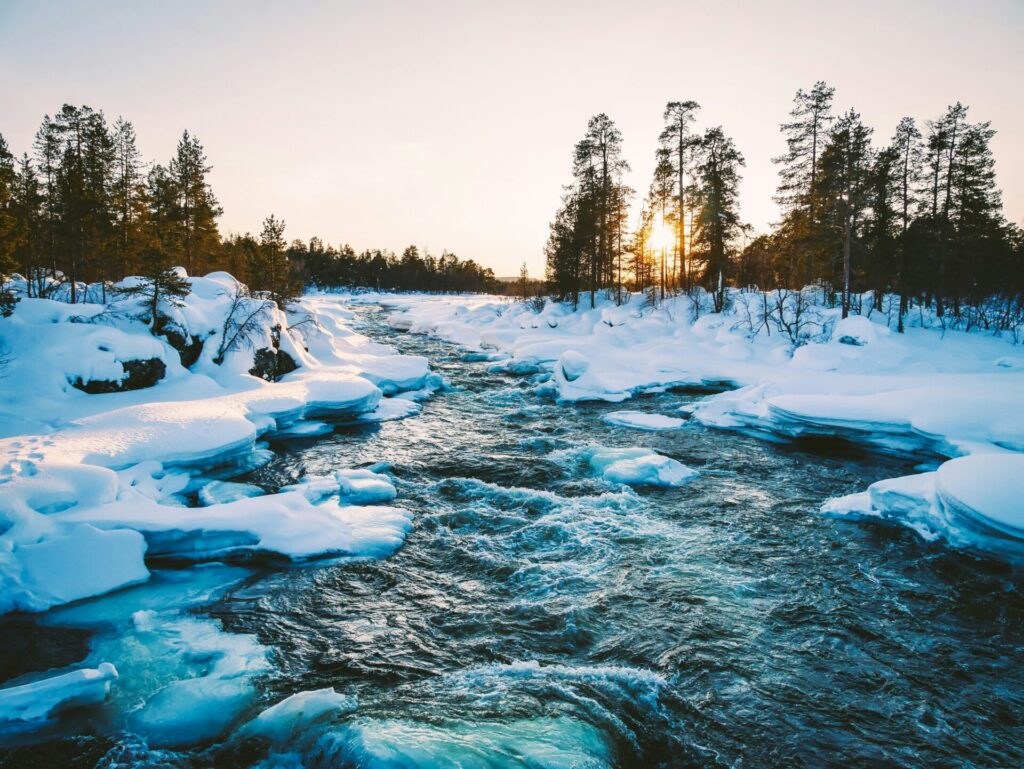 river running through snow at sunset