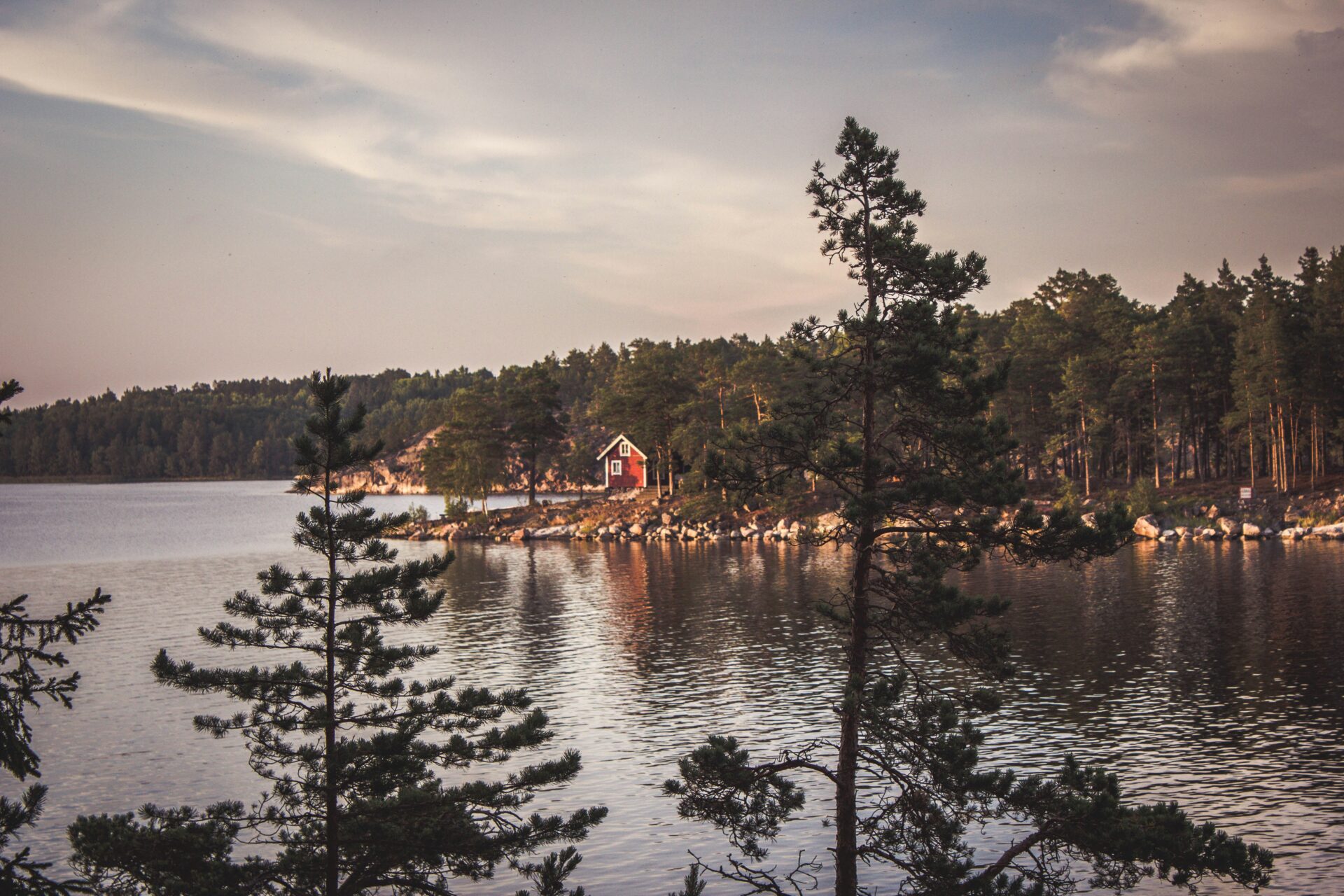 red cabin by the lake surrounded by trees