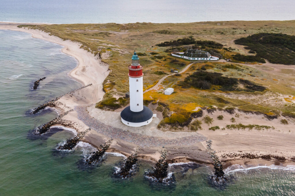 white and red lighthouse by coast