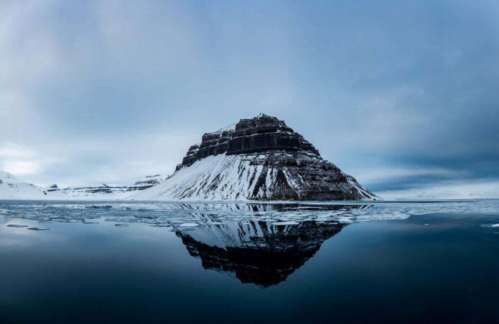 snow covered mountain by the sea in arctic