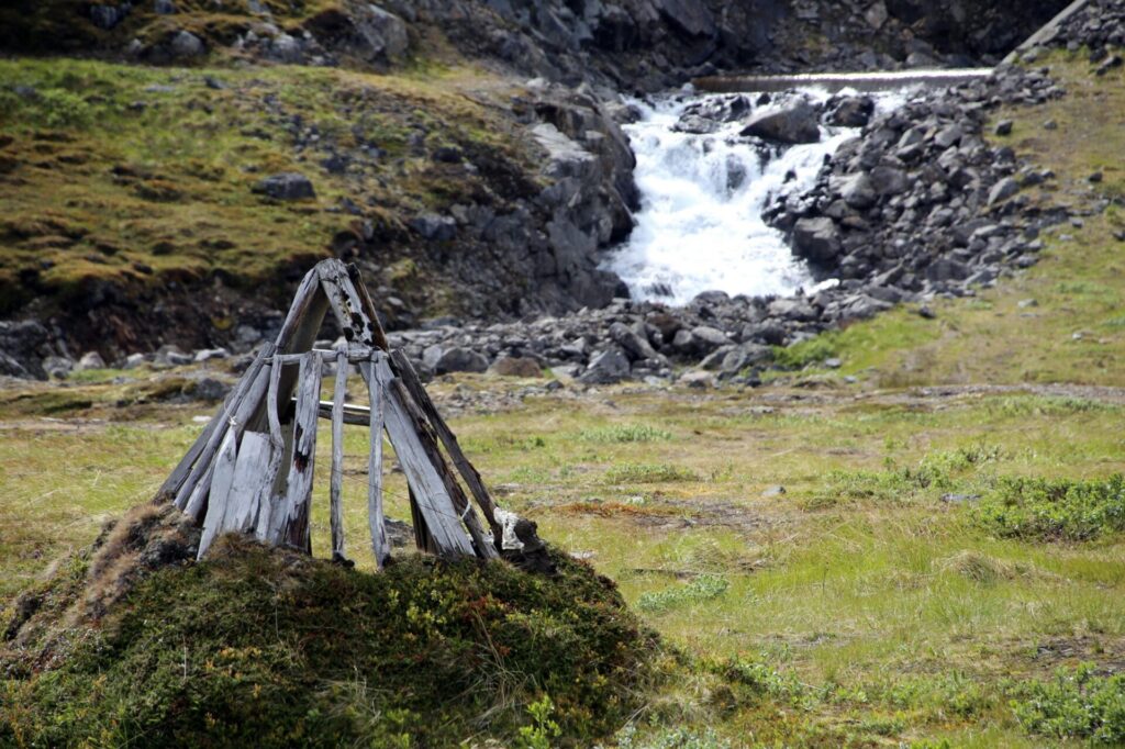 wooden sami hut by a small waterfall
