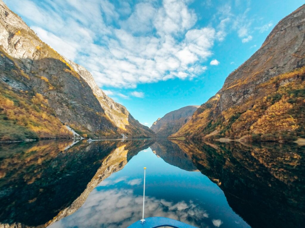 fjord in mountains seen from a boat with mirror like water