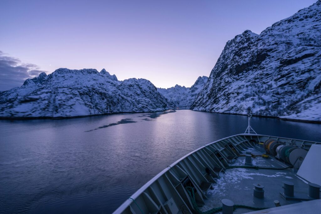 fjord and moutains seen from boat covered with snow sunset