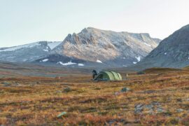 gray tent on green grass field near brown mountain during daytime in Sweden