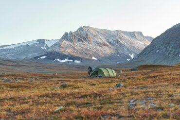 gray tent on green grass field near brown mountain during daytime in Sweden