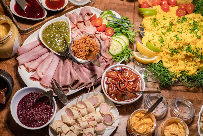 A Swedish smorgasbord comes with an assortment of cold cuts, herring, sauces and scrambled eggs.
