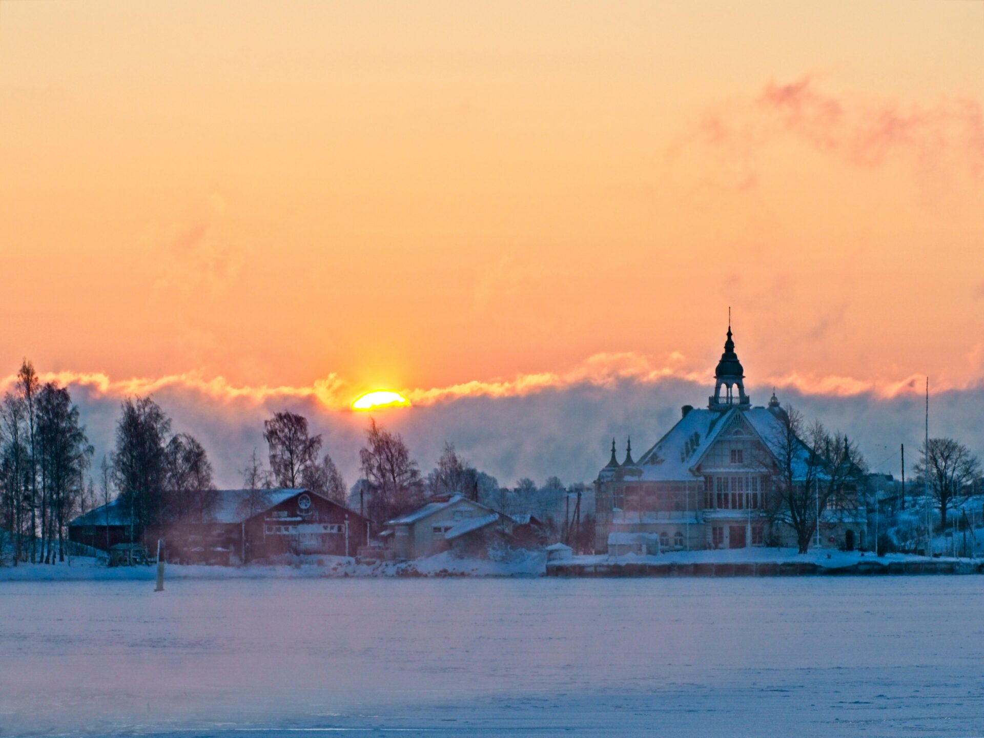 sun setting over a snowy icy landscape and a church in the clouds