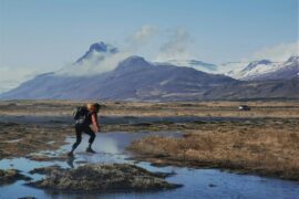 man jumping over stream in the mountains