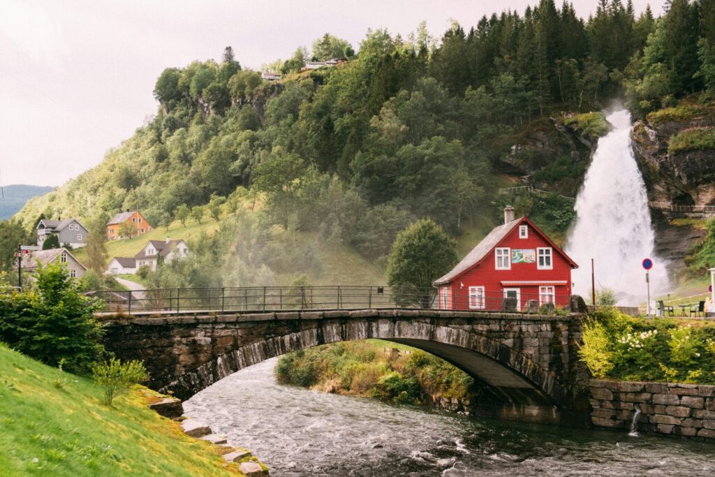 red cabin by river with waterfall