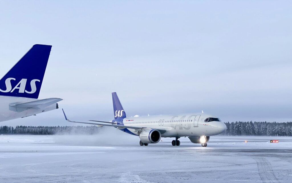 SAS airplane in snow with trees in background
