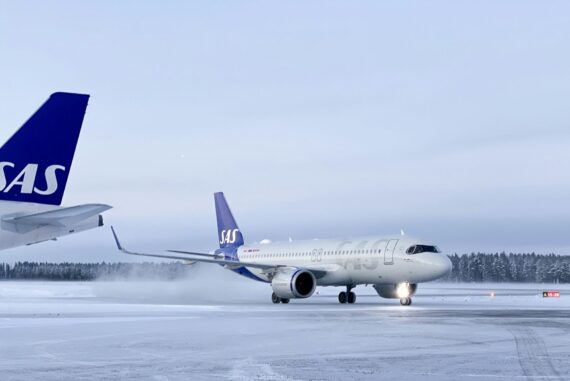 SAS airplane in snow with trees in background