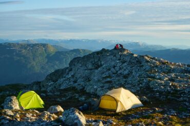 two tents with dramatic mountains in the background: this is camping in Norway