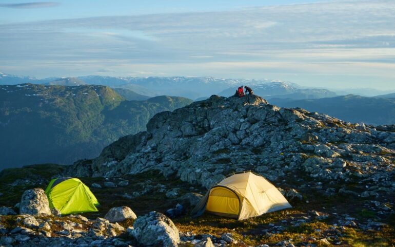 two tents with dramatic mountains in the background: this is camping in Norway
