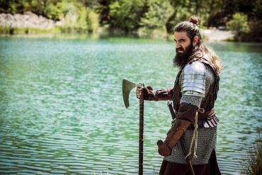 viking with axe standing by a lake