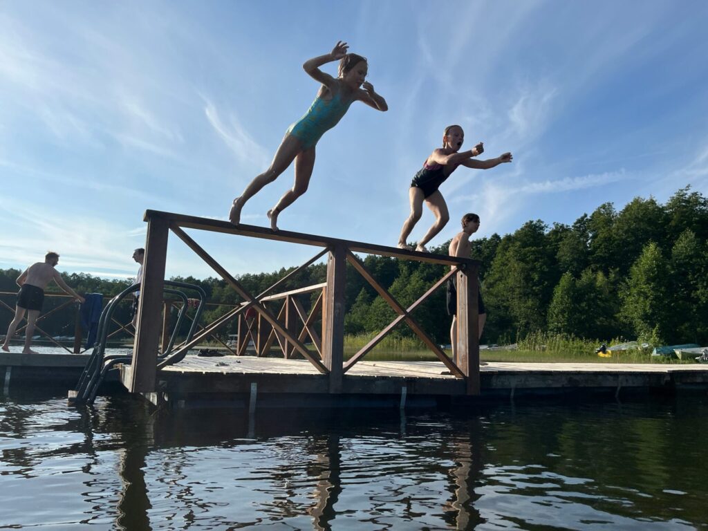 girls jumping in the lake from a floating dock