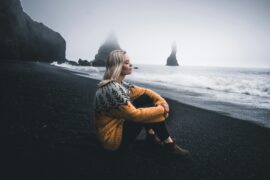 girl sitting by the sea stormy weather