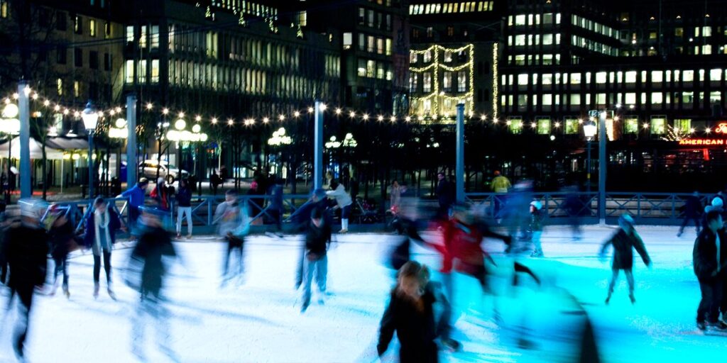 people ice skating in town in the dark with lights