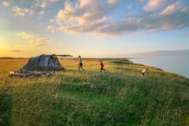 adults with toddler tent in a field by the sea