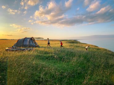 adults with toddler tent in a field by the sea